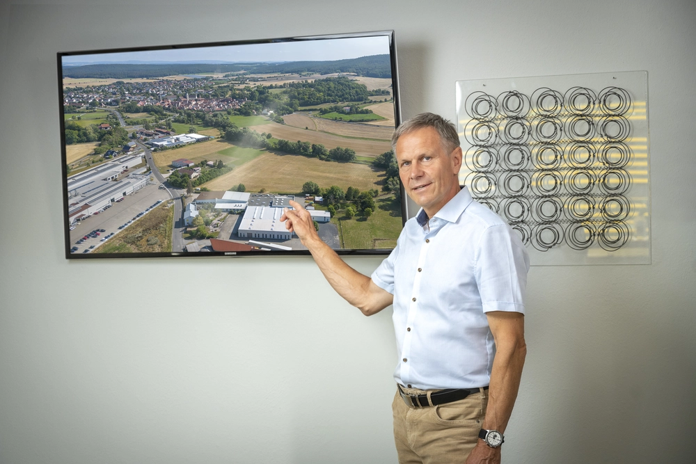 © Fotografie Hesselbach, Background e.K. - für Hoffmann GmbH / Sonstige/Kommerziell Gerhard Hoffmann vor einem Fotos des Firmensitzes der Hoffmann GmbH Seßlach.