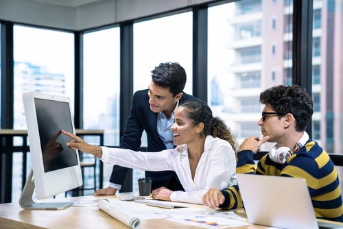 3 Personen am Schreibtisch vor dem Computer